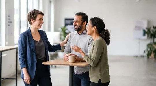 Dirigeant et collaborateurs echangeant naturellement dans un bureau lumineux, symbole d'une organisation flexible et humaine