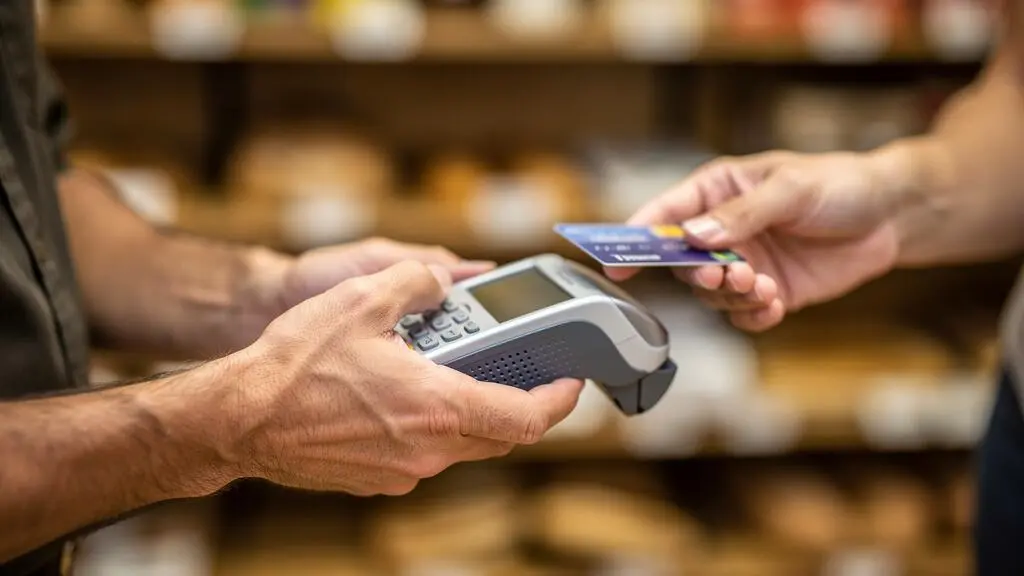 Commerçant utilisant un terminal de paiement électronique lors d'une transaction avec un client dans une boutique française